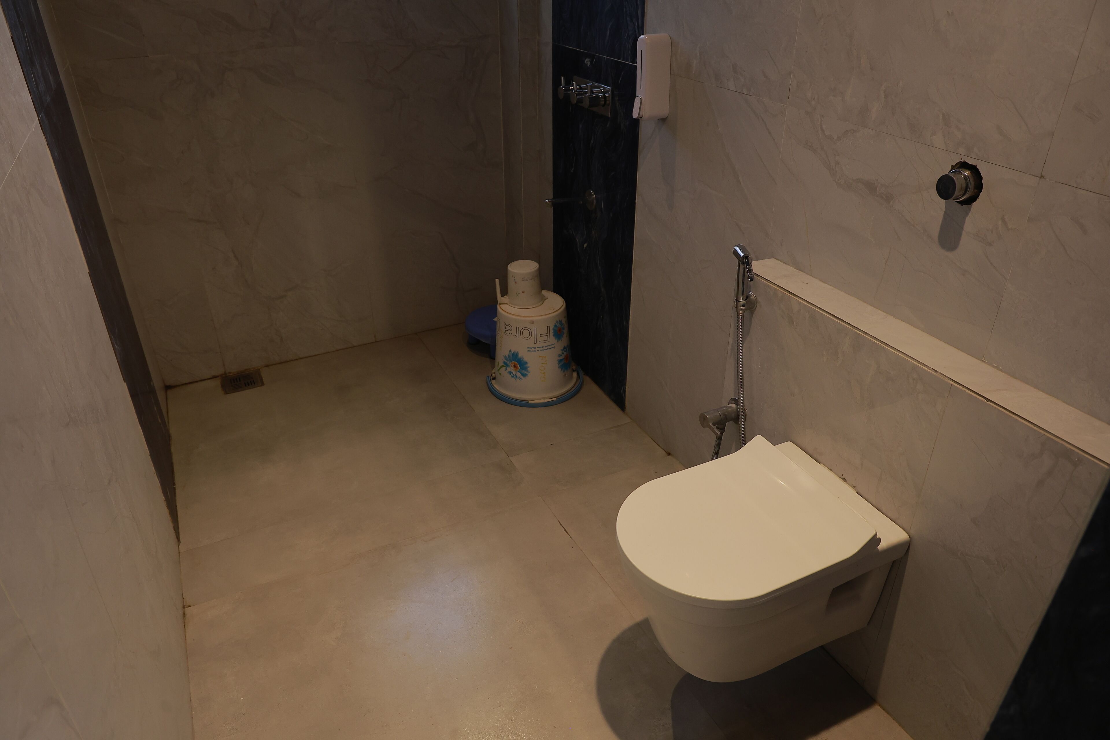 A bathroom with a toilet, a shower area, and a toilet paper dispenser.