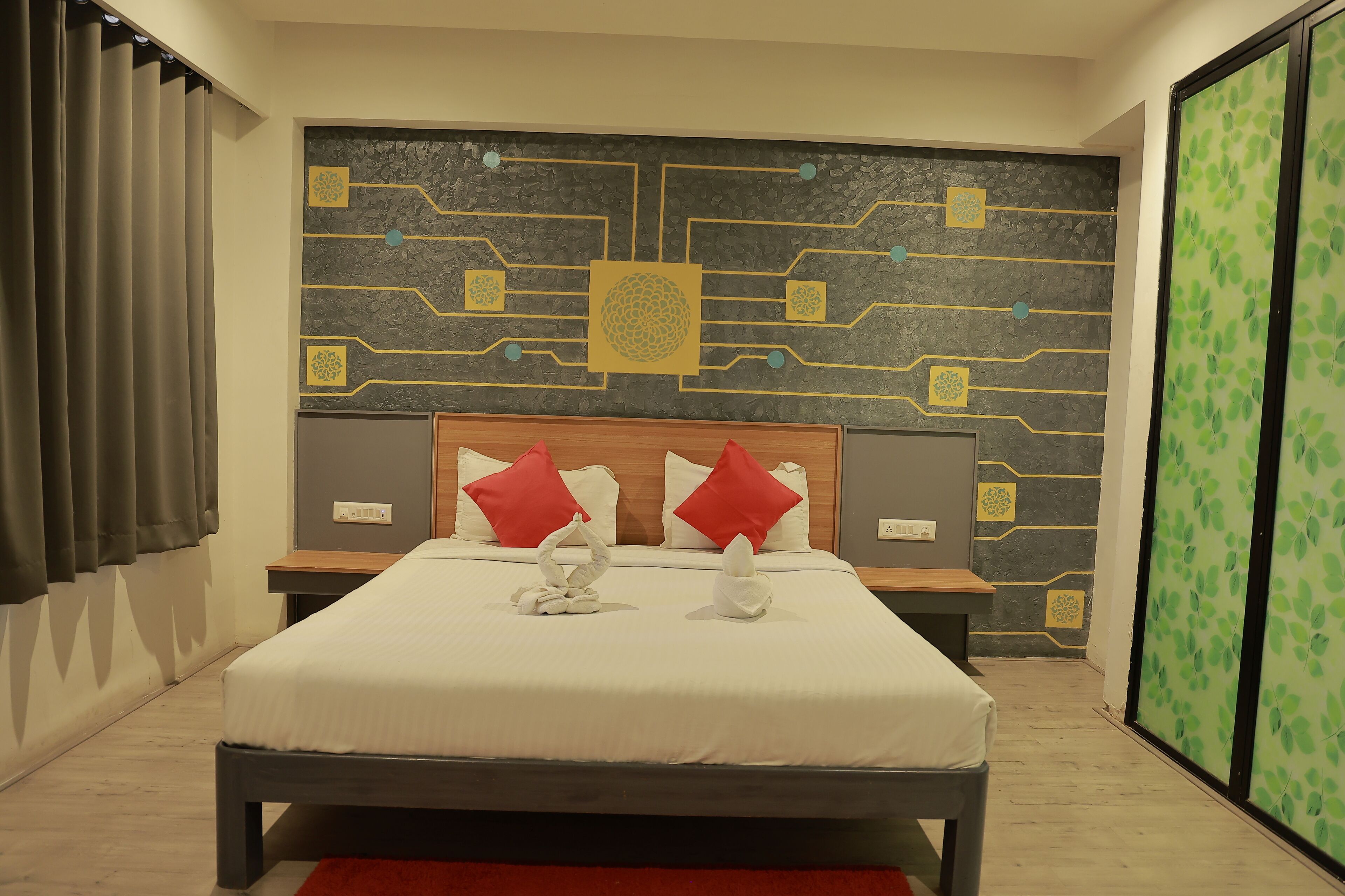 A neatly made bed with red pillows, a wall with a geometric pattern, and a green leaf-patterned sliding door.