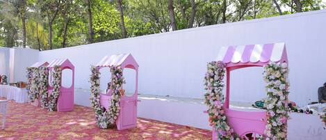 A pink kiosk with floral decorations and a red carpeted floor.