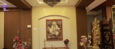 A reception area with a wooden desk, a framed portrait, and a decorative statue.