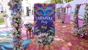 Un colorido arreglo floral y un letrero que dice "CARNIVAL Party of Raj & Asha".
