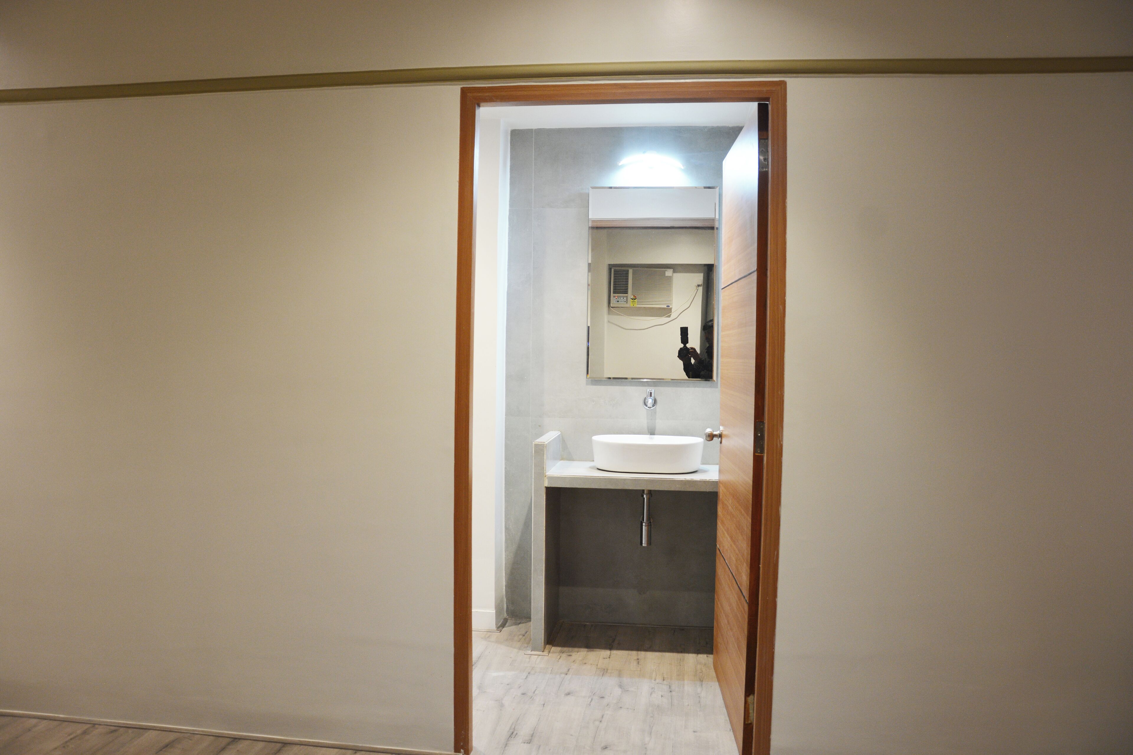 Un baño con lavamanos blanco, un espejo y una puerta que da a otra habitación.