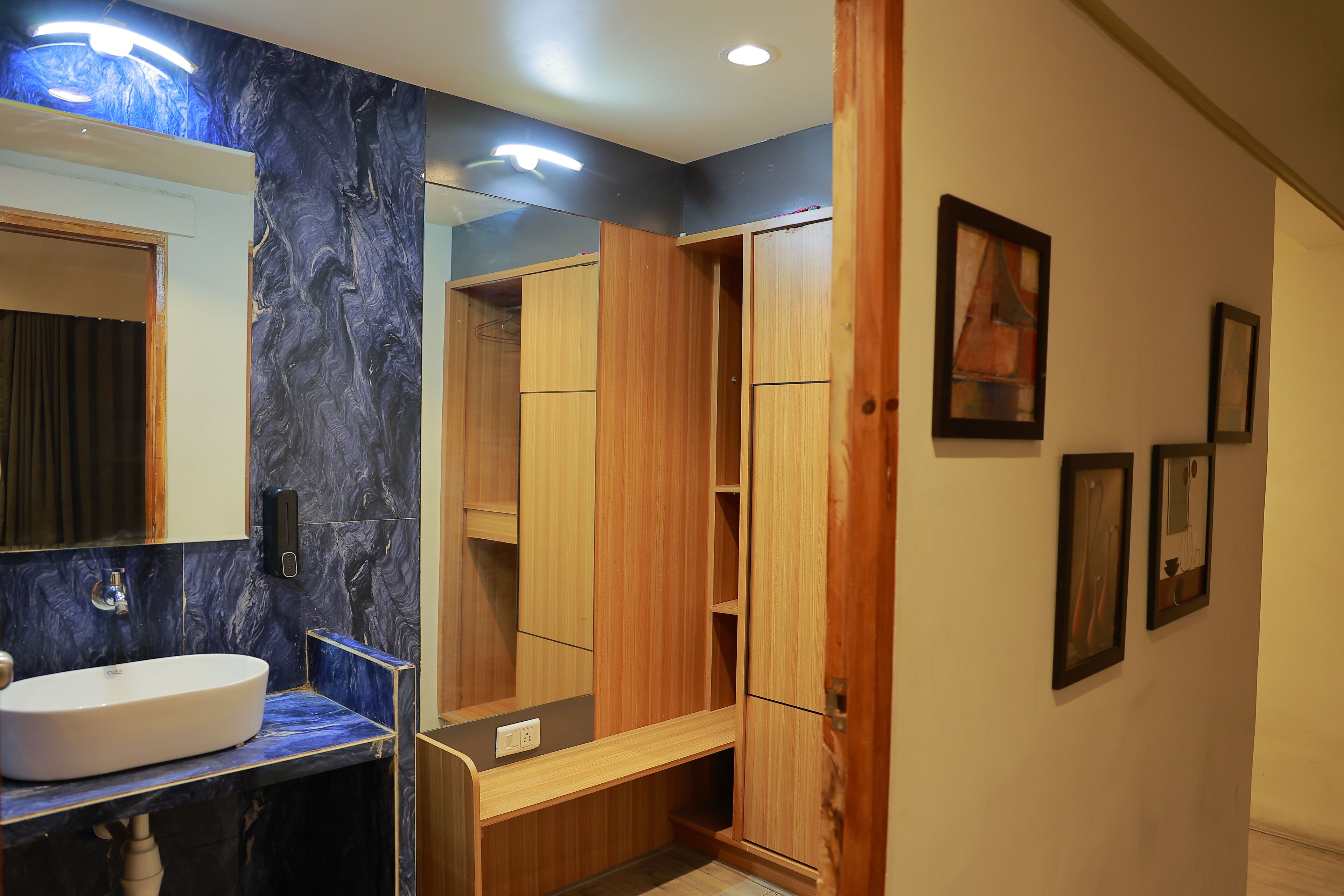 A bathroom with a marble sink, wooden vanity, and a large mirror.