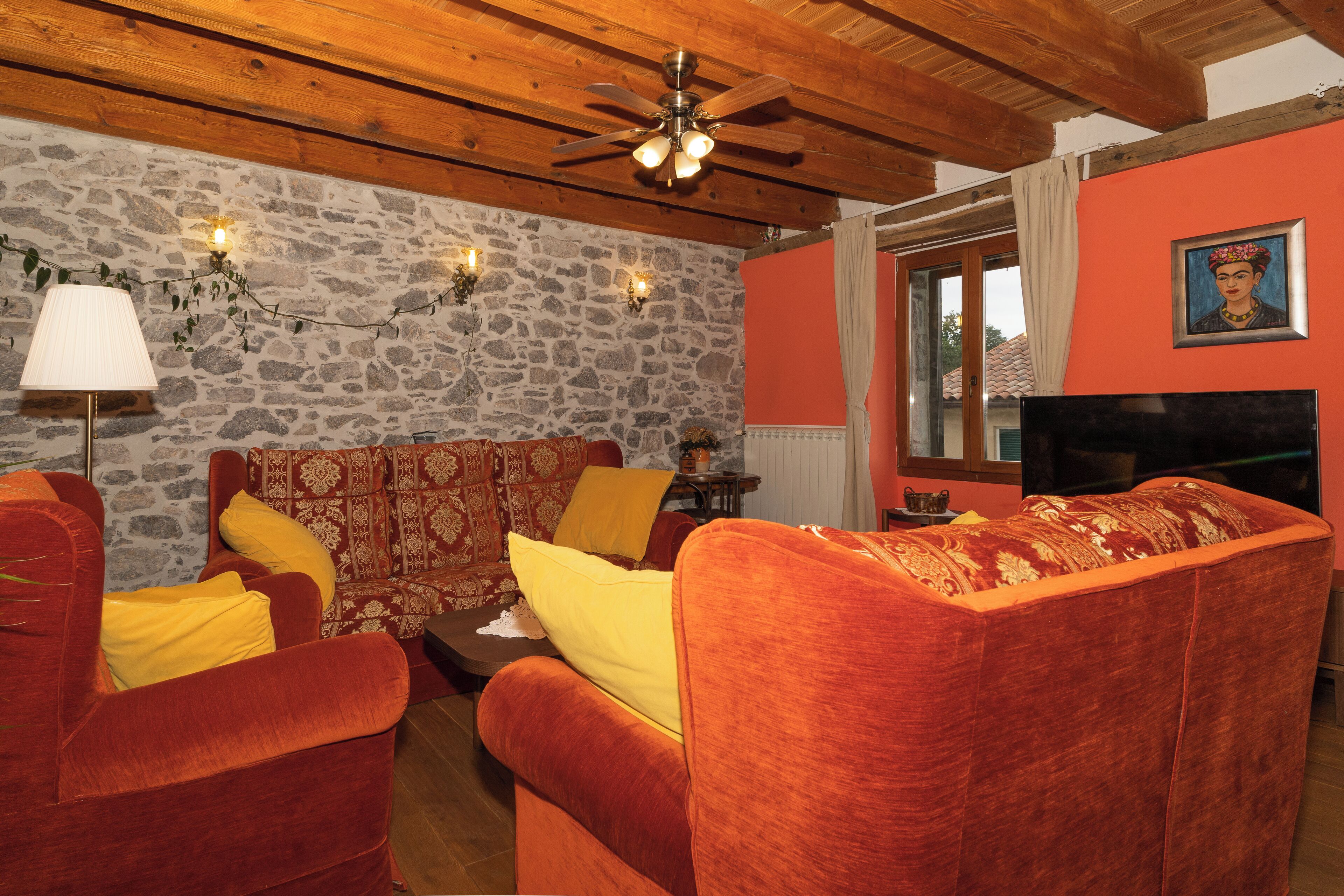 Una sala de estar acogedora con pared de piedra, techo de madera y un conjunto de sofás.