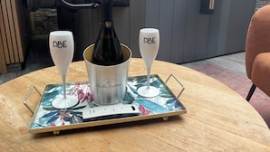 A table with a bottle of champagne and two glasses labeled "DBE" on a tray with a floral design. - Love Room with private spa  (Le Perrier)
