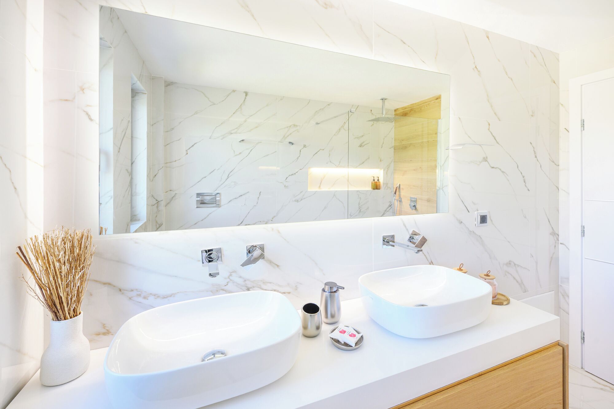 A bathroom with two sinks, a large mirror, and a wooden vanity.