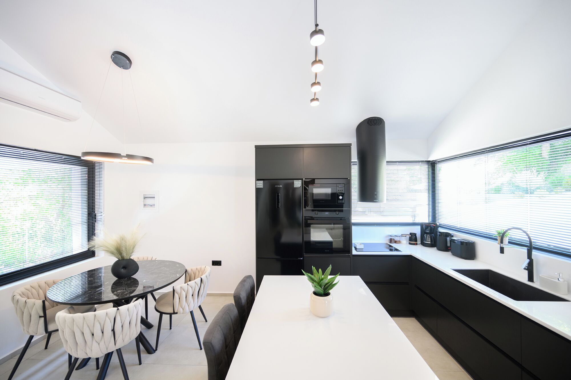 Cocina moderna con una isla central, electrodomésticos negros y un comedor con una mesa redonda y sillas acolchadas.