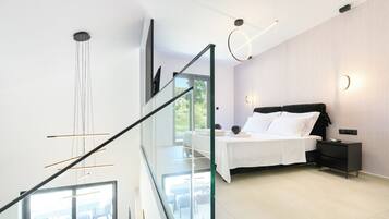 Un dormitorio moderno con cama, mesita de noche y vistas al exterior a través de un ventanal.