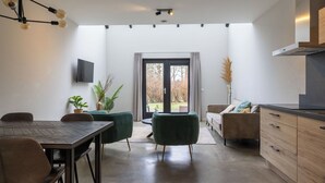 A modern kitchen with a dining area, a TV mounted on the wall, and a large sliding glass door leading to an outdoor area. - Beautiful private villa for 4 guests with WIFI, TV, terrace and pets allowed (Veere)