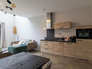 Une cuisine moderne avec des meubles en bois, un four encastré et un coin repas doté d’une table au motif en chevrons.