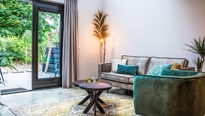 A modern living room with a sofa, armchair, and a coffee table. There is a large window with a view of greenery outside. - Beautiful private villa for 4 guests with WIFI, TV, terrace and pets allowed (Veere)