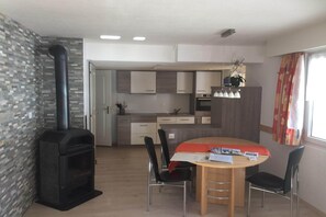 Uma cozinha moderna com uma ilha central, uma área de jantar com mesa redonda e uma lareira a lenha.