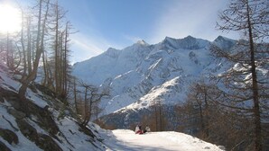 A snow-covered mountain road with two people sitting on a sled. - Chalet Stadel: Alpine Comfort (Saas Grund)