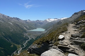 Un paysage de montagne avec un lac, un sentier rocheux et un ciel dégagé.