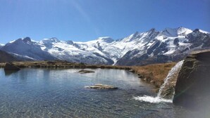 A mountain landscape with a clear lake and a waterfall. - Chalet Stadel: Alpine Comfort (Saas Grund)