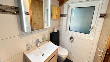 Een badkamer met een wit wastafel, spiegel en toilet.