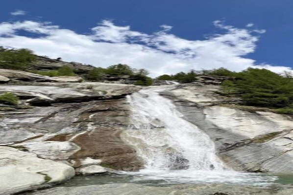 A waterfall cascading over rocky terrain with sparse vegetation.