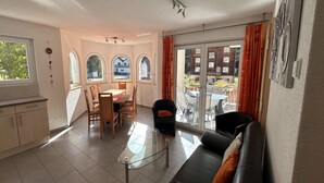 Een moderne woonkamer met een glazen salontafel, een bank en een eethoek met een tafel en stoelen.