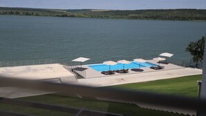 A pool area with lounge chairs and umbrellas, overlooking a large body of water. - Plein Air Residence & Resort (Vatra)