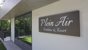 A sign for "Plein Air Residence & Resort" with a modern design and a view of the surrounding greenery. - Plein Air Residence & Resort (Vatra)