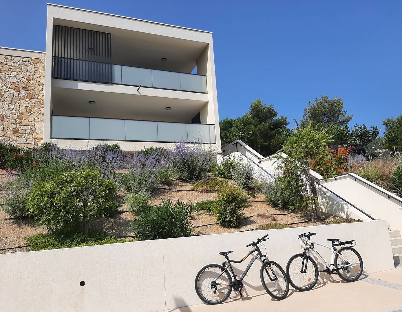 A modern building with a stone facade and a flat roof. There are two bicycles parked in front.