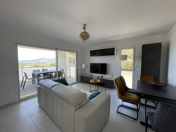 Relax in this stylish living space with a comfortable sofa, flat-screen TV, and dining area, plus a balcony with a view of the surrounding landscape.