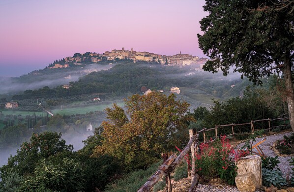 A historic hilltop town with buildings on a hillside, surrounded by greenery and a misty atmosphere. - Stelle di Monte (Montepulciano)