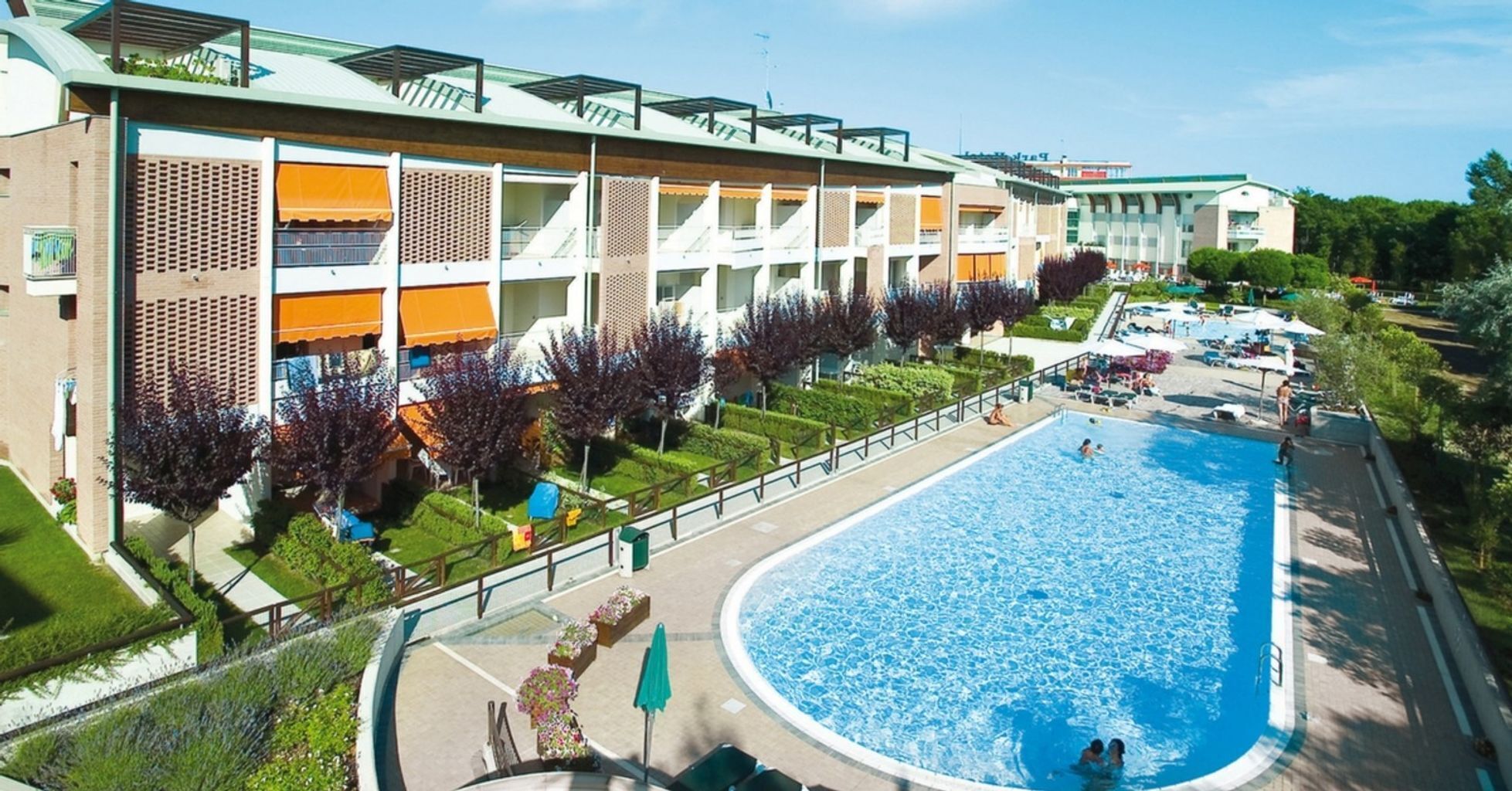 Un hôtel doté d’une grande piscine, de nombreux balcons et d’un jardin bien entretenu.