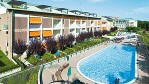 Ein Hotel mit einem großen Schwimmbad, mehreren Balkonen und einem gepflegten Garten.