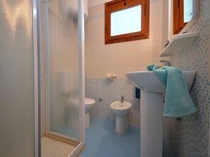 A bathroom with a shower, toilet, bidet, and sink.