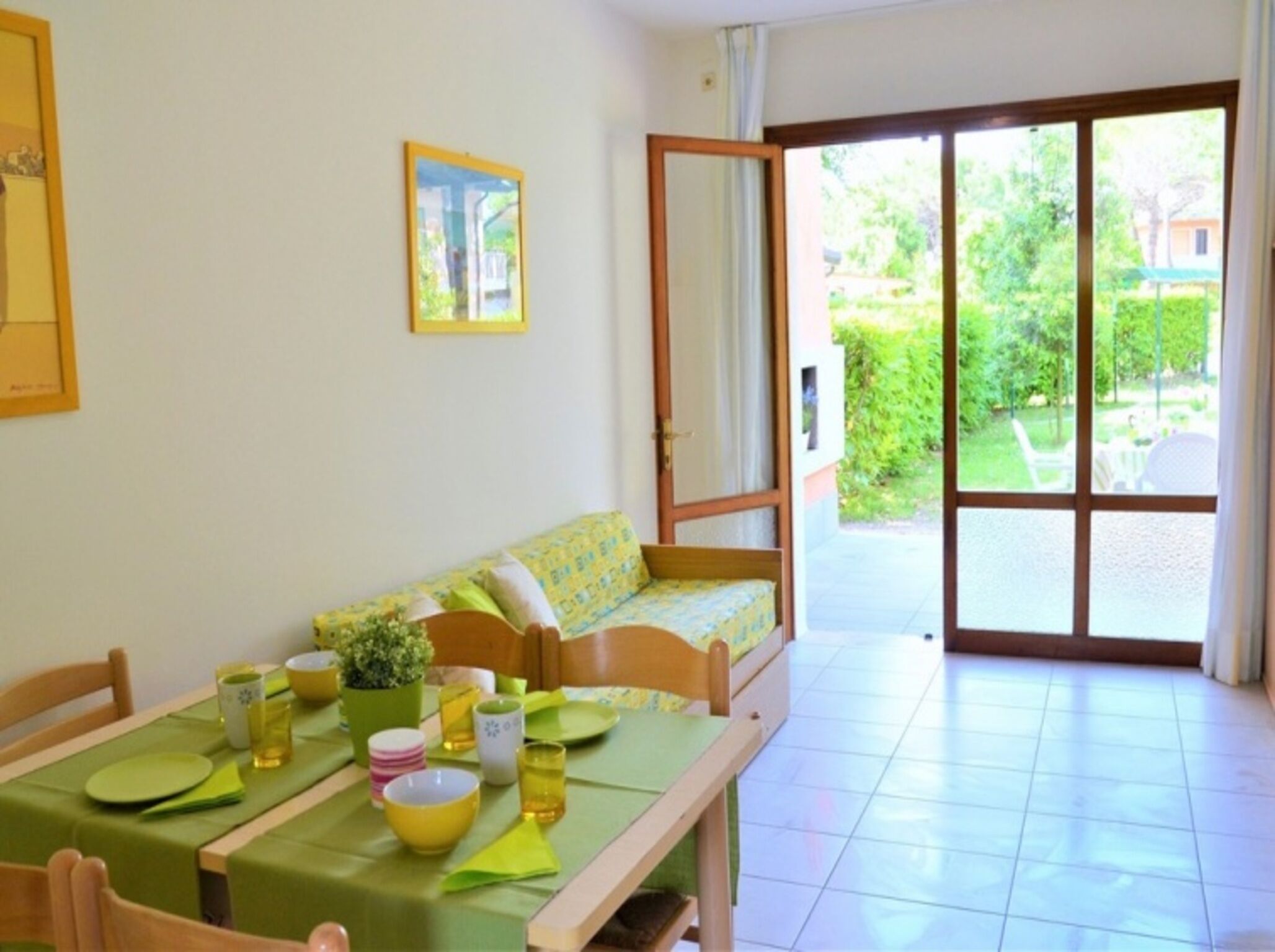 A cozy room with a dining table set for two, a sofa, and a sliding glass door leading to a garden.