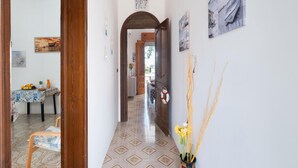 Un corridoio con piastrelle decorate, una cornice di legno e un vaso con fiori gialli.