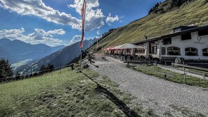 Vista sulle montagne con un ristorante chiamato 'SONNALM' e posti a sedere all'aperto.