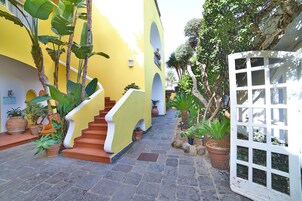 Un patio con un muro amarillo, una puerta blanca y una escalera.