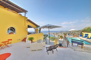 Una terraza con piscina, mobiliario exterior y vistas al mar.