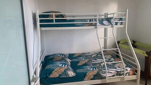 A bunk bed with a tropical leaf-patterned bedspread and a white metal frame. - La p'tite caz Béa  (L'Étang-Salé)