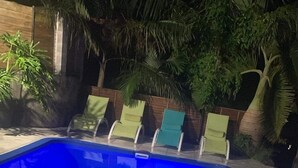 A swimming pool with a blue hue, surrounded by a wooden fence and palm trees. - La p'tite caz Béa  (L'Étang-Salé)