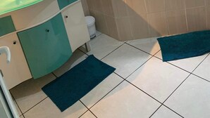 A bathroom with a bathtub, a sink with a mirror, and a toilet. - La p'tite caz Béa  (L'Étang-Salé)