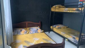 A dormitory room with bunk beds, a wooden headboard, and floral-patterned bedding. - La p'tite caz Béa  (L'Étang-Salé)