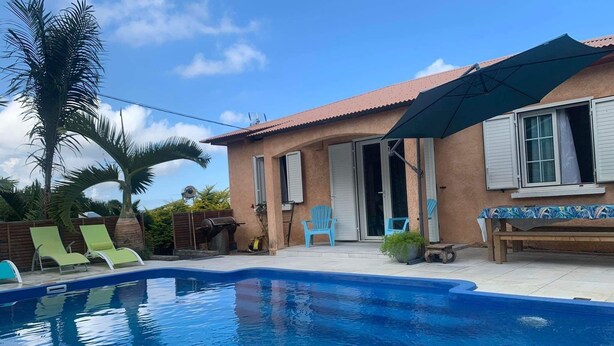 A swimming pool with lounge chairs and a patio area. - La p'tite caz Béa  (L'Étang-Salé)