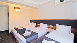 A hotel room with three single beds, a bedside table with a phone, and a wall-mounted air conditioner. - Diamond Hotel Old City (Istanbul)