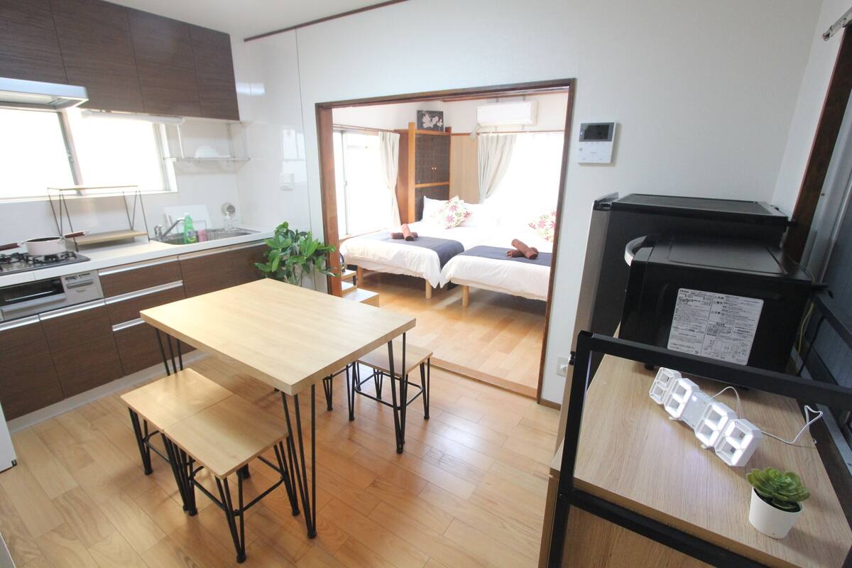 A compact kitchen with a dining area, a bed with a canopy, and a small table with a power strip.