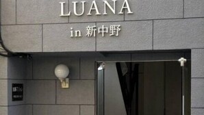 Een hotelentree met een bord waarop 'Hotel LUANA in 新中野' staat.