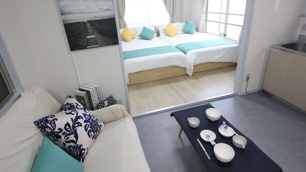 Een knus kamertje met een bed, een klein tafeltje met servies en uitzicht op het groen.