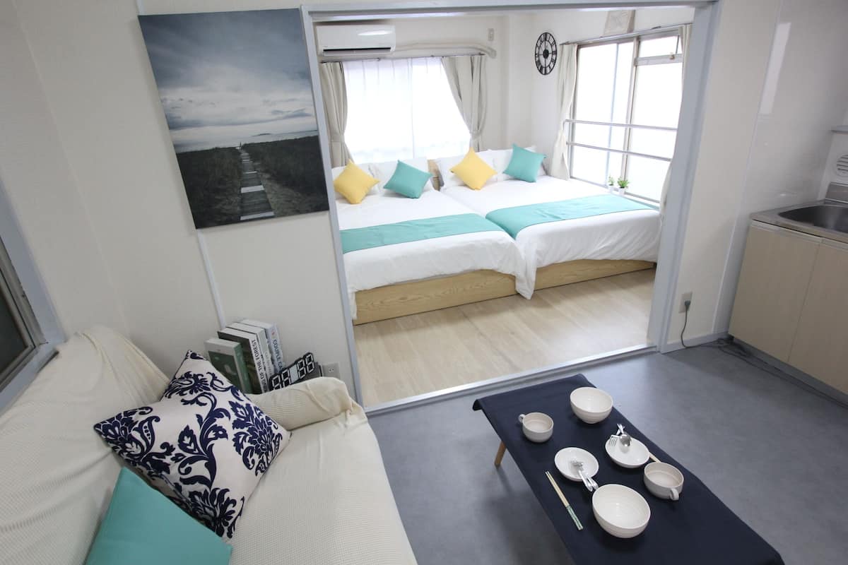 A compact room with a bed, a small table with dishes, and a view of the outdoors.