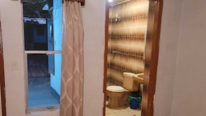 A bathroom with a toilet, a shower, and a window with a curtain. - Motel Vic-Mar (Ciudad Juárez)
