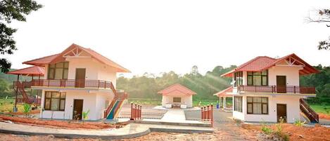 A bungalow-style hotel with a central building and two wings, each with a red-tiled roof and a balcony.