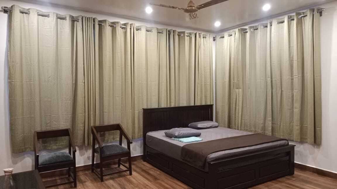 A bedroom with a bed, two chairs, and a ceiling fan.