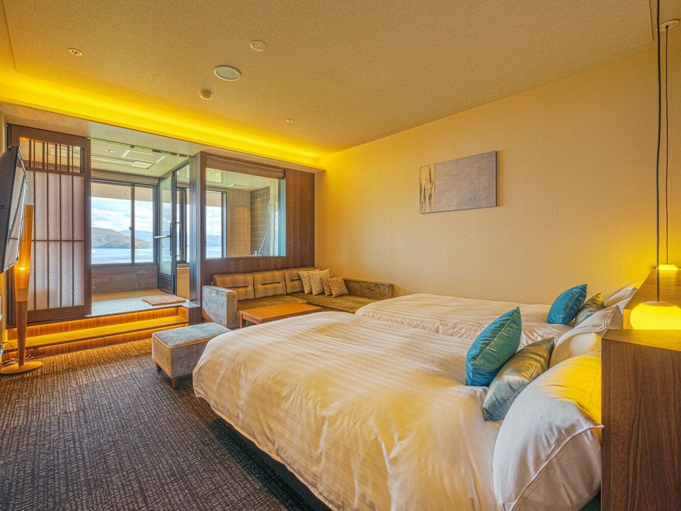A bedroom with a large bed, a seating area, and a view of the outdoors.