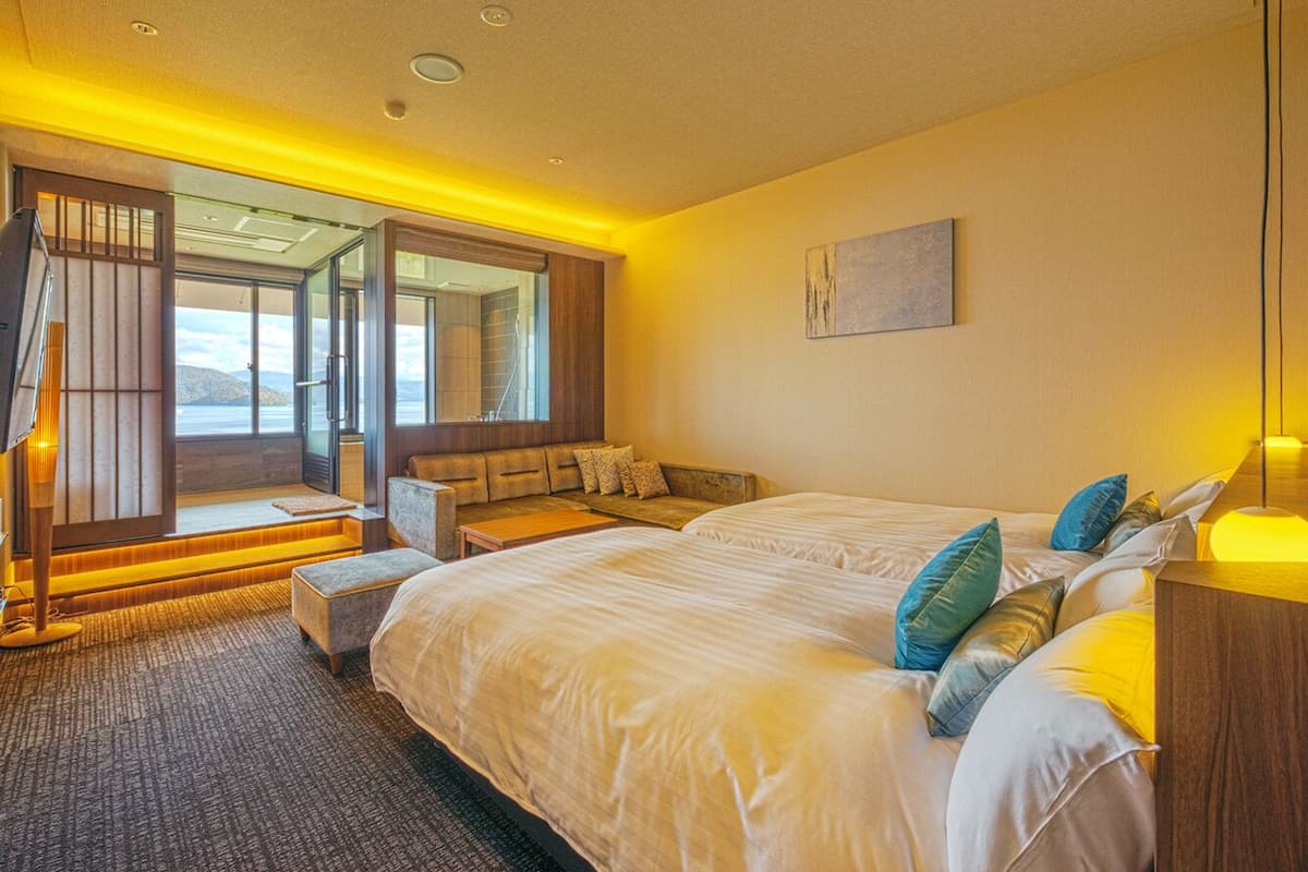 A bedroom with a large bed, a seating area, and a view of the outdoors.